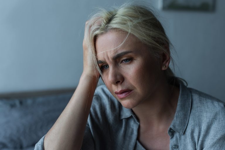Exhausted blonde woman having migraine during menopause